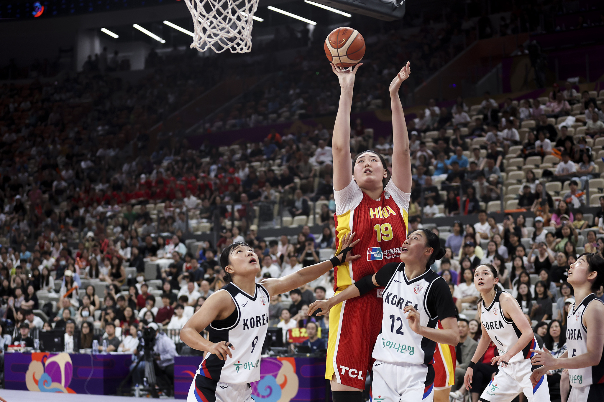 Zhang Ziyu (# 19) de la Chine prend un coup contre la Corée du Sud lors du troisième match à la Fiba Women's Asia Cup à Shenzhen, la province du Guangdong en Chine du Sud, le 20 juillet 2025. / VCG