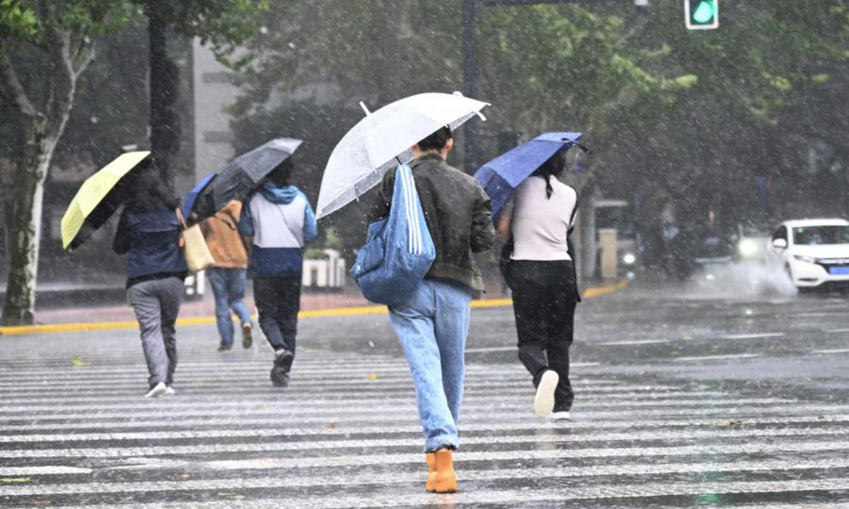 People walk across a street in the rain in Shanghai, east China, Nov. 1, 2024. (Photo by Chen Haoming/Xinhua)