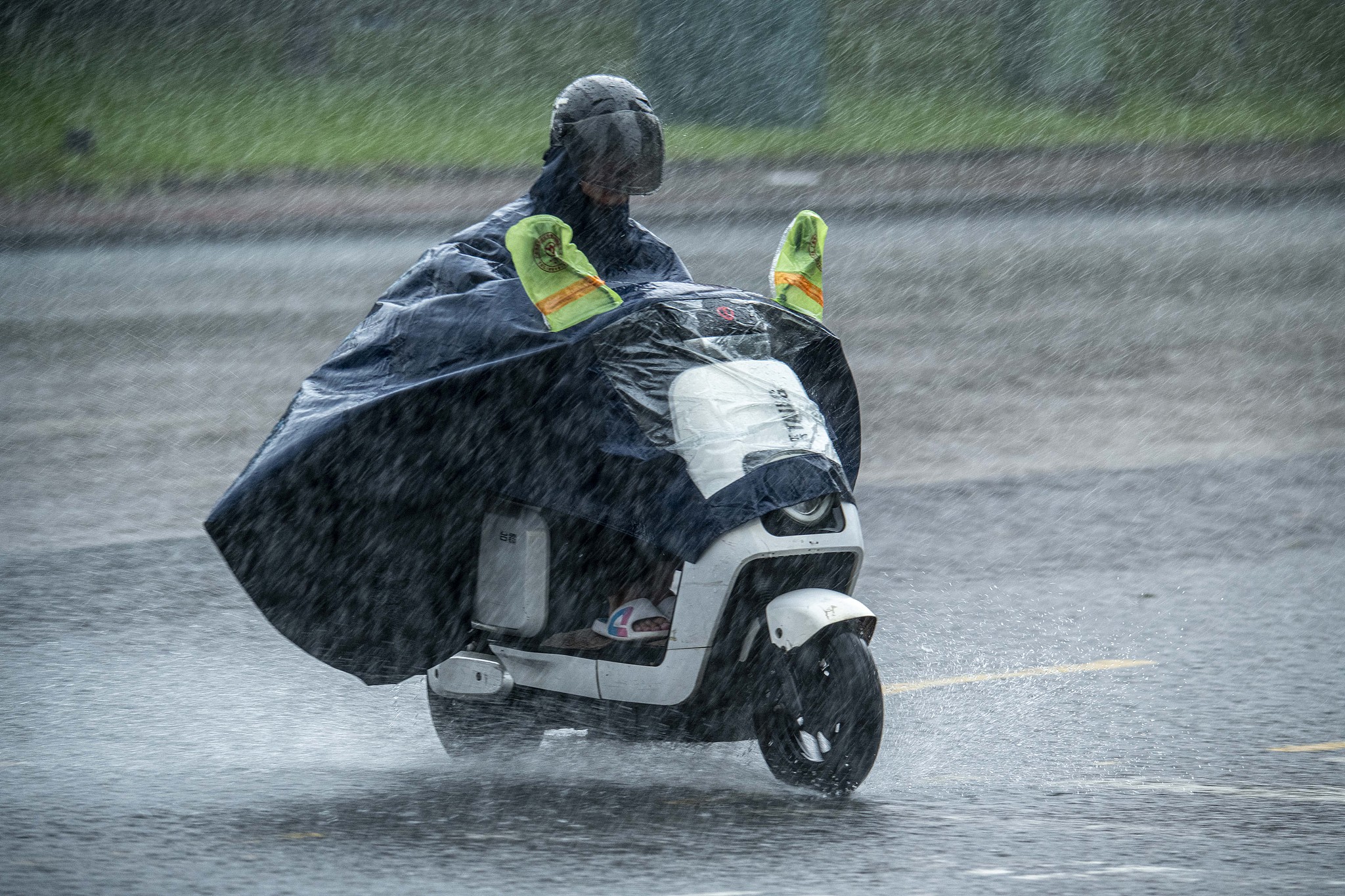 Une personne chevauche un scooter électrique sous la pluie à Qionghai, province de Hainan, sud de la Chine, 24 août 2025. / VCG