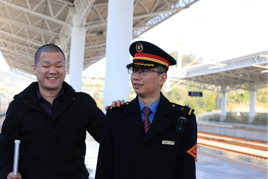 Sun Wufei (left), a visually impaired massage therapist from Ningde, South China’s Fujian Province, stands with Ye Yaojun, a duty passenger service clerk at Fuding Railway Station. Photo: Cheng Jun