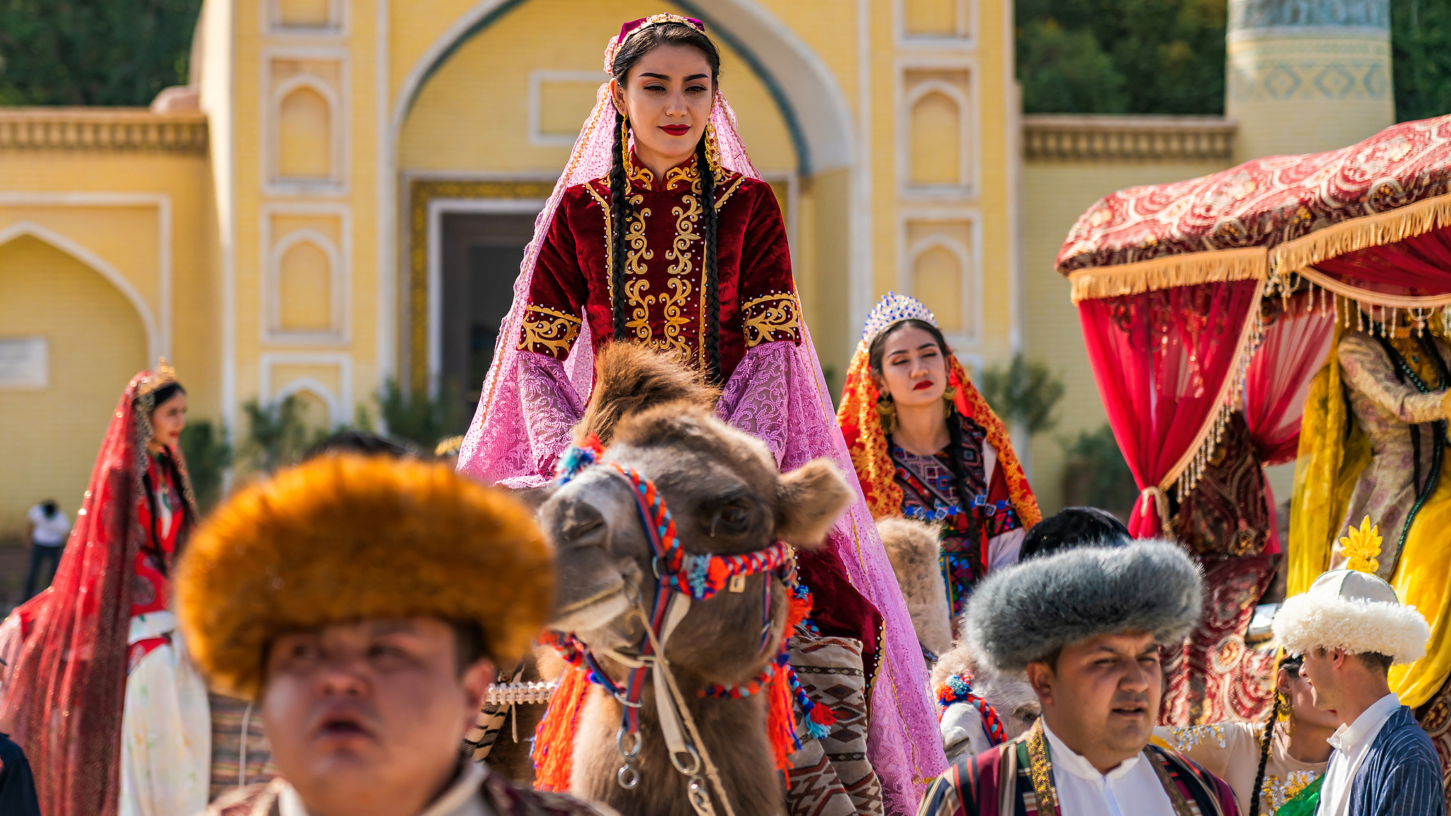 Des jeunes Ouïgours en costume traditionnel effectuent un défilé de caravanes de chameaux sur l'ancienne Route de la Soie, sur une place devant une mosquée à Kashi, dans la région autonome ouïgoure du Xinjiang, le 23 septembre 2020. /CFP