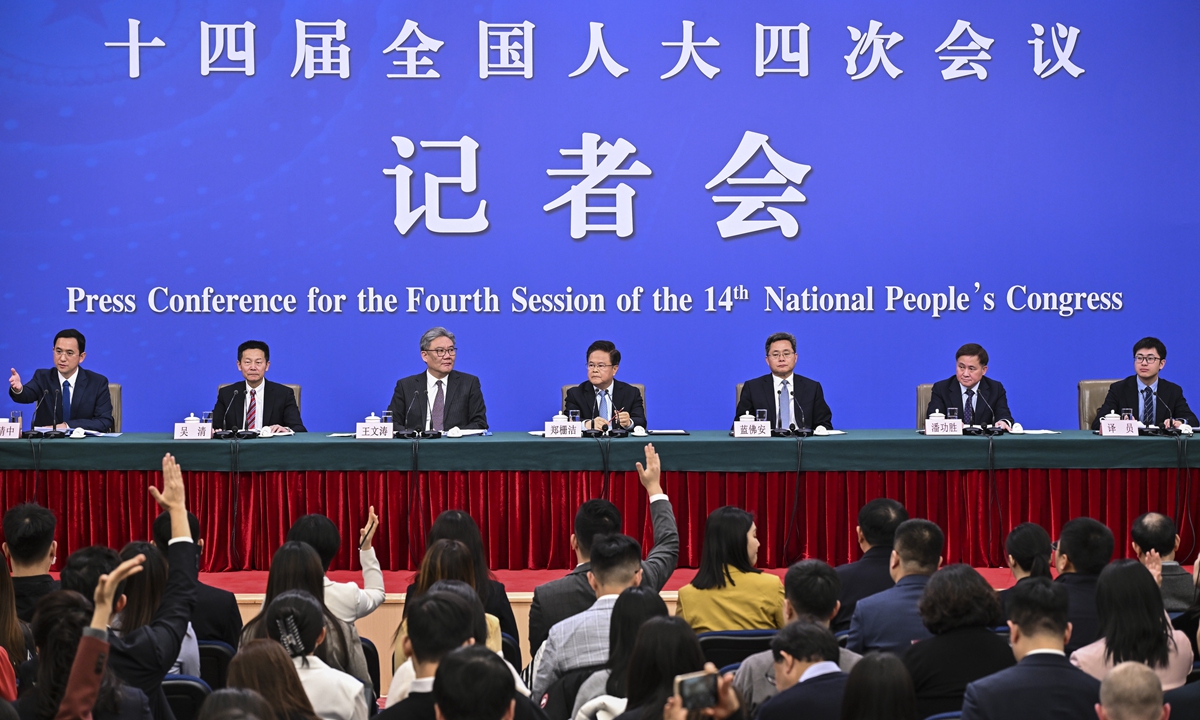 Journalists raise hands to ask questions at a press conference for the fourth session of the 14th National People