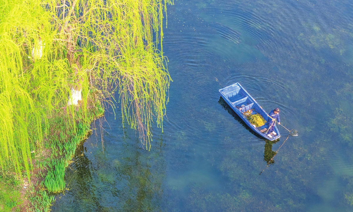 A staff member cleans up floating debris on Xuanwu Lake in Nanjing, East China