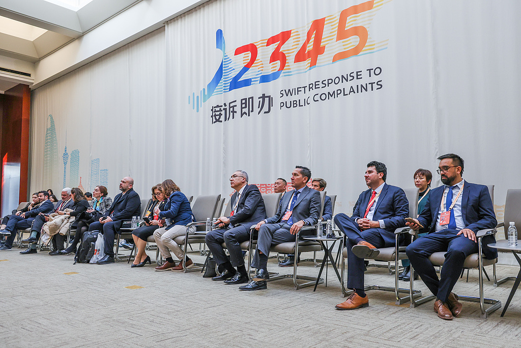 Des invités internationaux visitent le centre de service d'assistance téléphonique pour les citoyens 12345 de Pékin pour en savoir plus sur le mécanisme de réponse rapide aux plaintes du public de la ville, à Pékin, en Chine, le 17 décembre 2024. /VCG