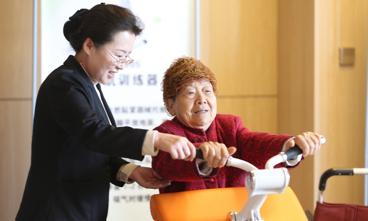 A staff member assists an elderly person with exercise at a fitness center in Rizhao, East China
