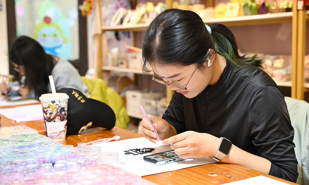 A college student works on a perler bead artwork at a shop in Shichahai, a famous scenic area in the northwest part of Beijing, on November 7, 2025. Photos on this page: VCG