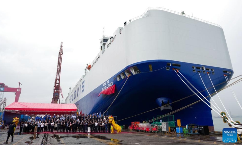 Guests pose for a group photo at the delivery ceremony of car carrier Glovis Leader in Guangzhou, south China