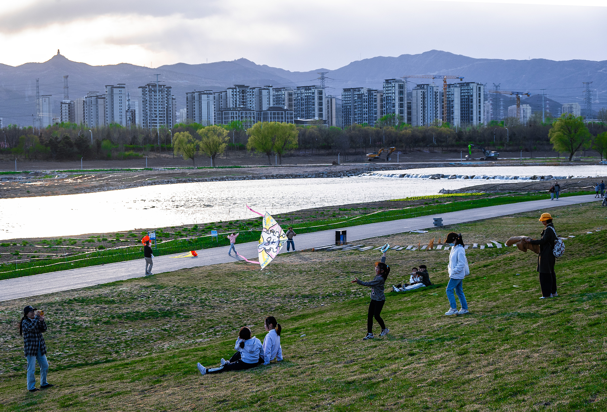 Les gens profitent du printemps au bord de la rivière Yongding, Pékin, Chine, le 5 avril 2026. /VCG